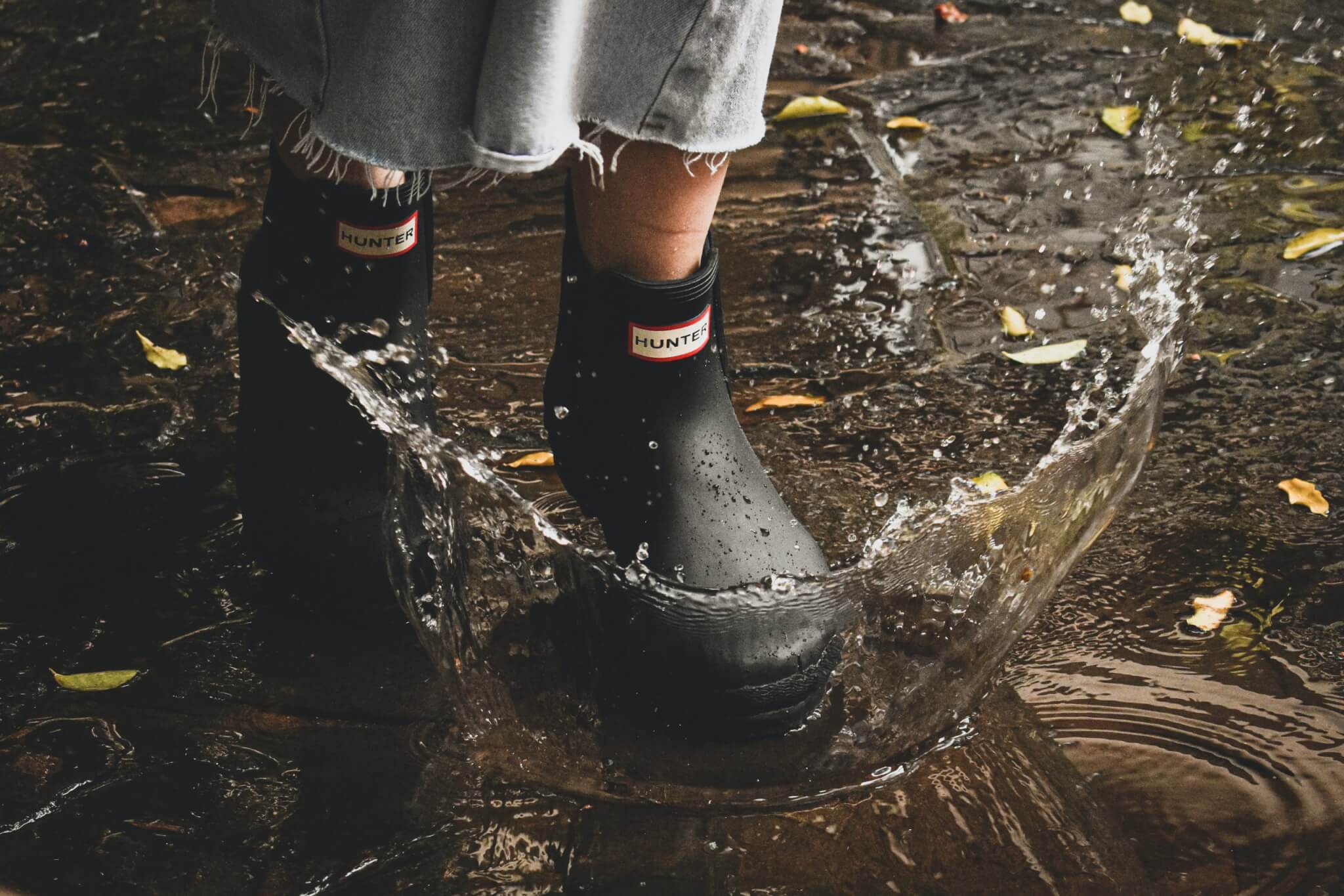 Birkenstock Store -Birkenstock Store Woman walking through puddle in Hunter rain boots scaled 1